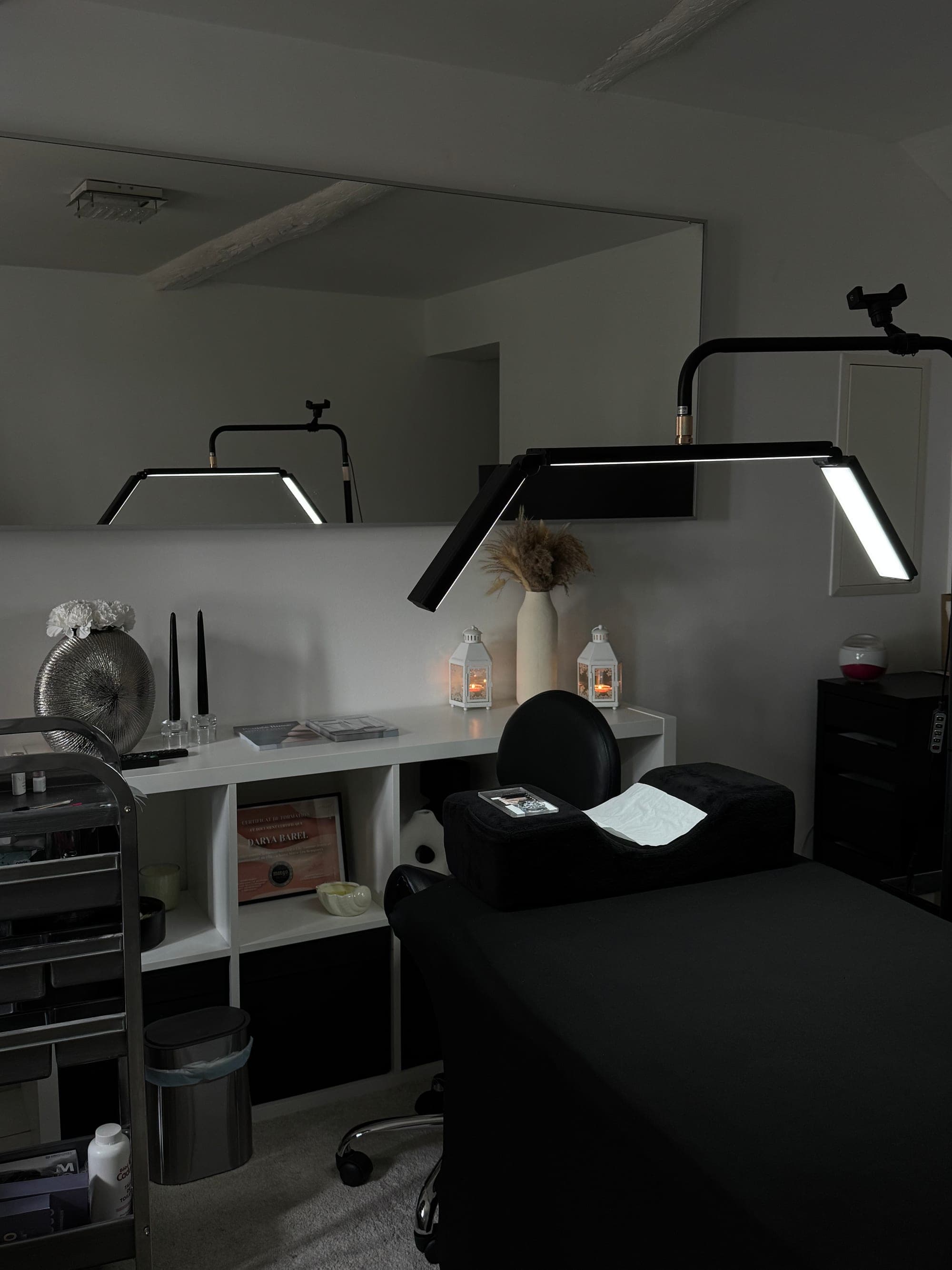 La cabine du studio : lit de soin noir, lampe LED et miroir
